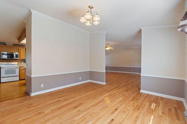 unfurnished dining area with crown molding, ceiling fan with notable chandelier, and light hardwood / wood-style flooring