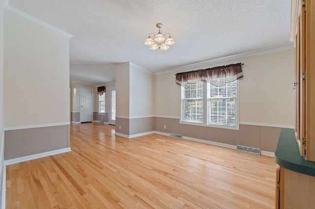 empty room featuring hardwood / wood-style flooring, ornamental molding, a healthy amount of sunlight, and a notable chandelier