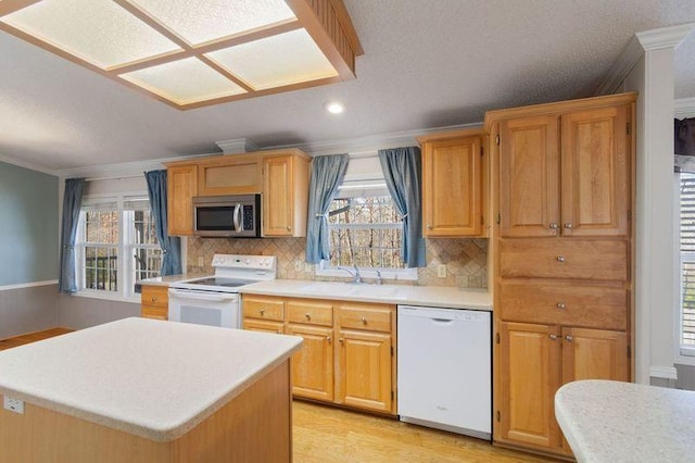 kitchen featuring sink, crown molding, light hardwood / wood-style flooring, a kitchen island, and white appliances