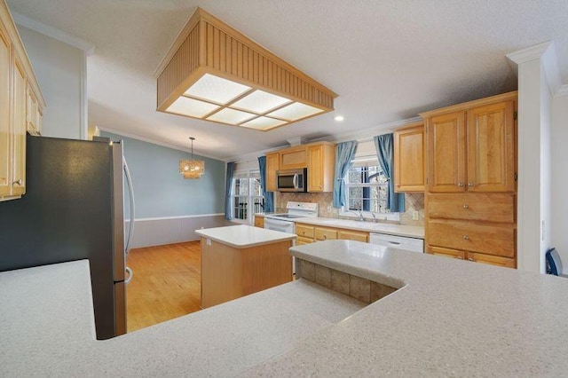 kitchen with hanging light fixtures, a center island, kitchen peninsula, stainless steel appliances, and crown molding