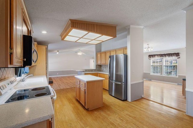 kitchen featuring sink, a center island, light wood-type flooring, appliances with stainless steel finishes, and ceiling fan