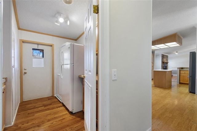 hallway with ornamental molding, a textured ceiling, and light wood-type flooring