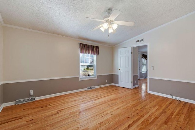 spare room with crown molding, vaulted ceiling, light hardwood / wood-style floors, and a textured ceiling