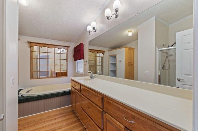 bathroom with crown molding, wood-type flooring, separate shower and tub, a textured ceiling, and vanity