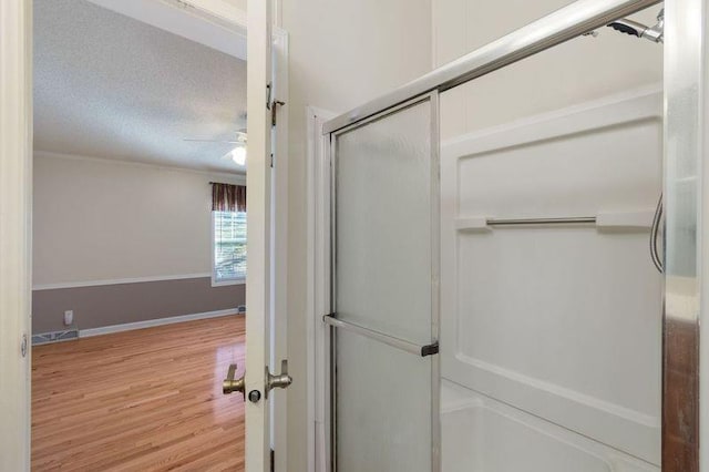 bathroom featuring hardwood / wood-style floors, ceiling fan, a textured ceiling, and walk in shower