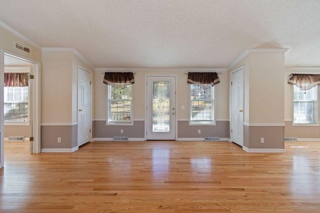 unfurnished room with a wealth of natural light, a textured ceiling, and light hardwood / wood-style floors