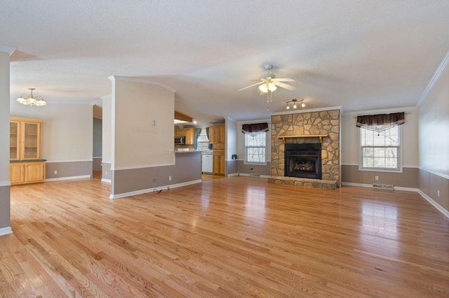 unfurnished living room featuring lofted ceiling, crown molding, light hardwood / wood-style flooring, a fireplace, and ceiling fan with notable chandelier