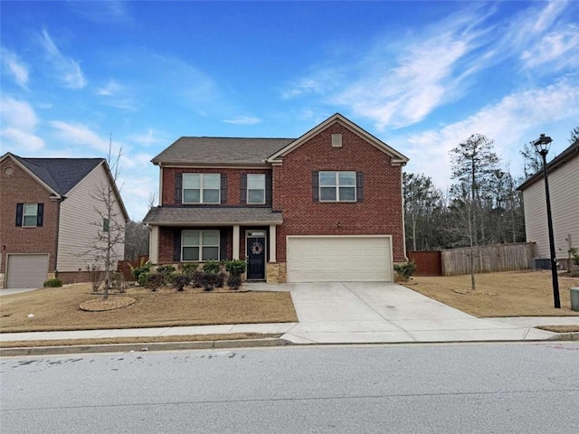 traditional-style home with driveway, brick siding, an attached garage, and fence