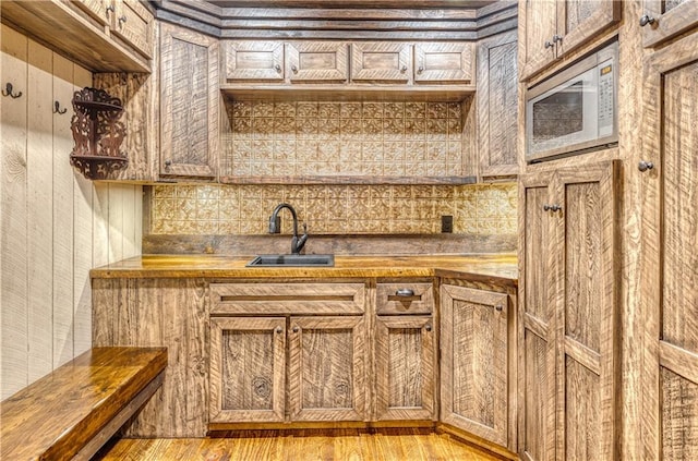 kitchen with light hardwood / wood-style flooring, white microwave, butcher block counters, and sink