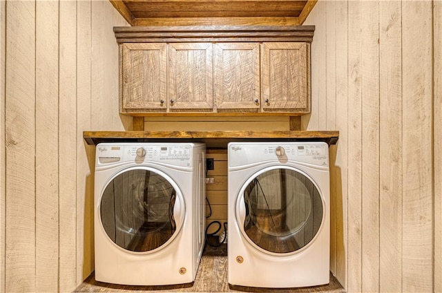 washroom with hardwood / wood-style flooring, cabinets, washer and clothes dryer, and wooden walls