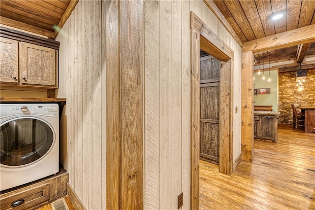 clothes washing area featuring washer / clothes dryer, light hardwood / wood-style flooring, cabinets, and wood ceiling