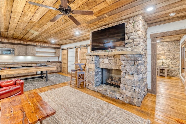 living room with wood ceiling, light hardwood / wood-style flooring, ceiling fan, and a barn door