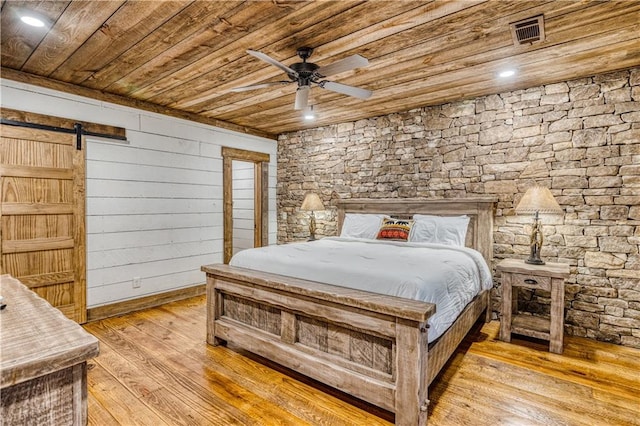 bedroom featuring wooden ceiling, light hardwood / wood-style flooring, ceiling fan, and a barn door