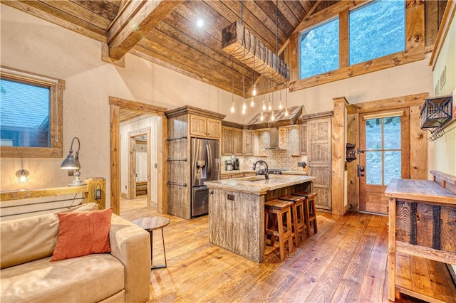 kitchen with backsplash, wooden ceiling, hardwood / wood-style floors, stainless steel refrigerator with ice dispenser, and a kitchen bar