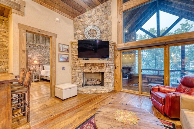 living room featuring hardwood / wood-style floors, high vaulted ceiling, wooden ceiling, and a fireplace