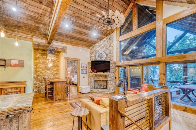 living room featuring wooden ceiling, light hardwood / wood-style floors, beamed ceiling, a stone fireplace, and high vaulted ceiling