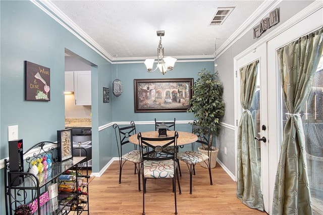 82 Twiggs Cor, Peachtree City, GA 30269 - dining space featuring light wood-type flooring, a chandelier, crown molding, baseboards, and a textured ceiling