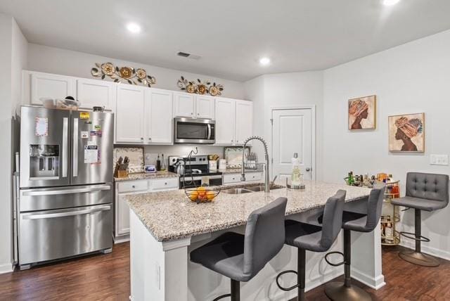 kitchen featuring white cabinets, an island with sink, and appliances with stainless steel finishes