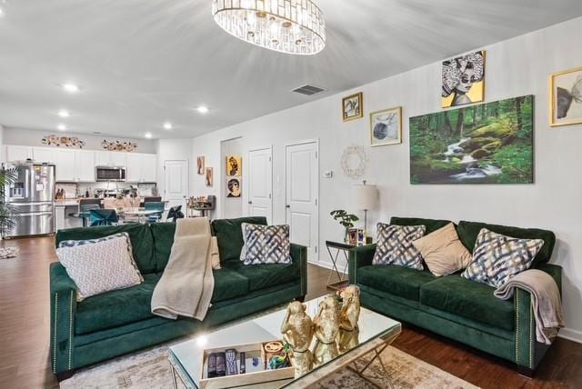 living room with dark wood-type flooring and an inviting chandelier