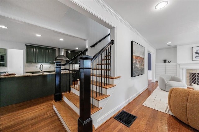stairs with crown molding, visible vents, baseboards, recessed lighting, and wood finished floors