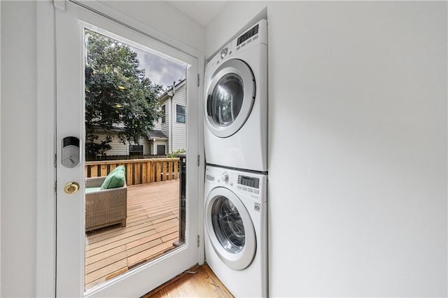 washroom with wood finished floors, stacked washing maching and dryer, and laundry area