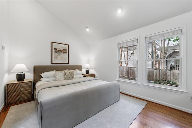 bedroom with recessed lighting, wood finished floors, lofted ceiling, and baseboards