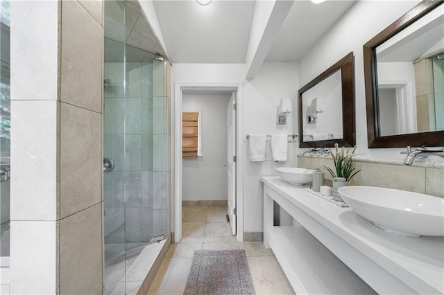bathroom featuring double vanity, baseboards, a stall shower, and a sink