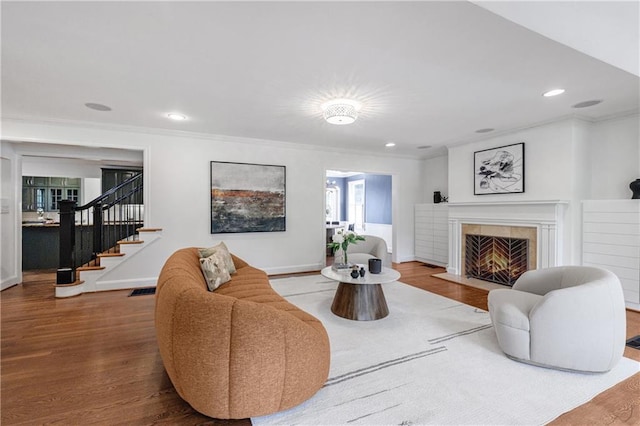 living room with wood finished floors, ornamental molding, and a fireplace