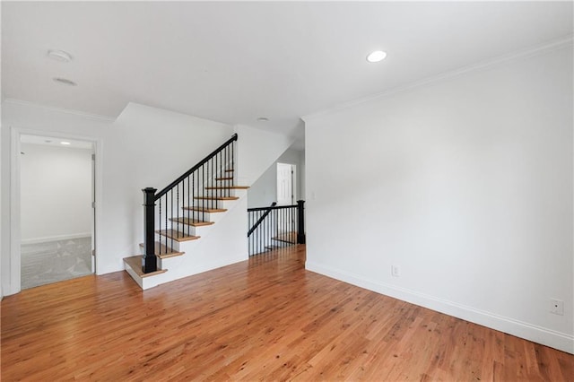 unfurnished living room with baseboards, ornamental molding, and light wood finished floors