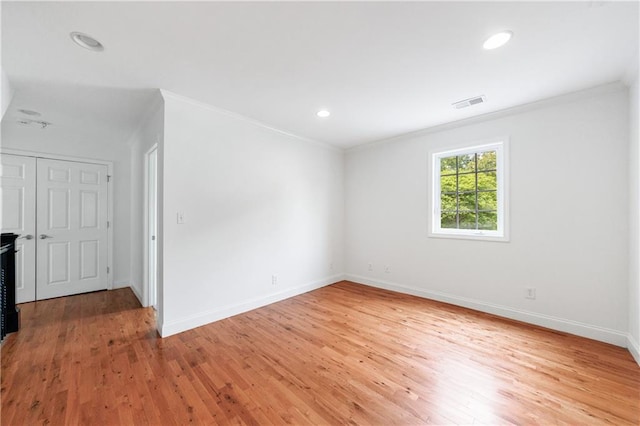 unfurnished room with light wood-style flooring, visible vents, ornamental molding, and baseboards