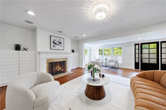 living room featuring baseboards, recessed lighting, ornamental molding, a fireplace, and wood finished floors