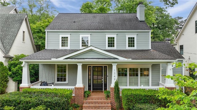view of front of property with a chimney, a porch, and a shingled roof