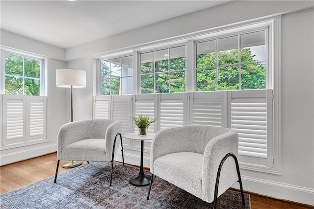 sitting room with a wealth of natural light, wood finished floors, and baseboards
