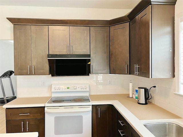 kitchen with decorative backsplash, dark brown cabinets, and white electric range oven