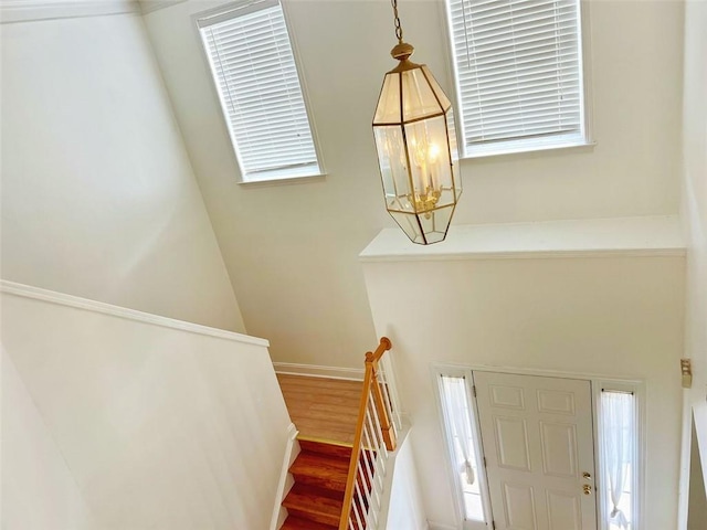 stairs with wood-type flooring and an inviting chandelier