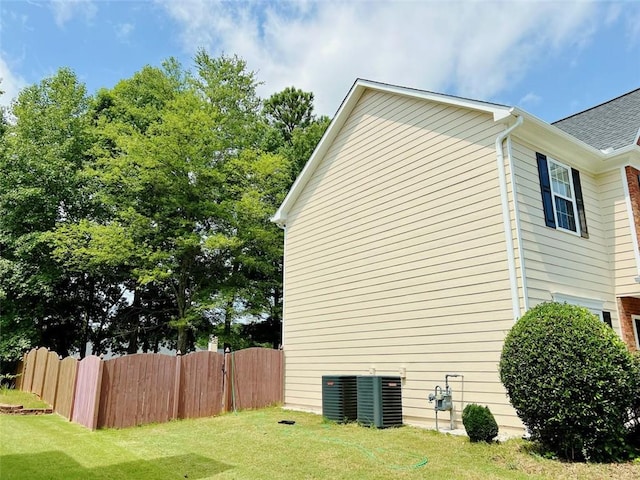 view of property exterior with a lawn and central AC unit