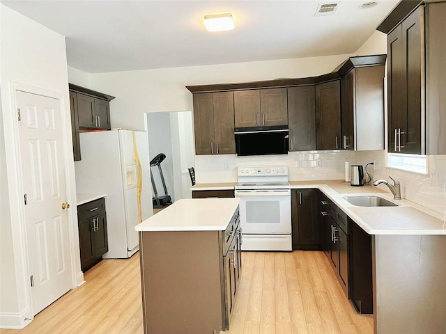 kitchen featuring a center island, light wood-type flooring, white appliances, and sink