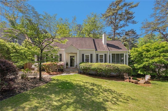 view of front of house featuring a front lawn, a chimney, and a sunroom