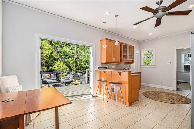 kitchen with light tile patterned floors, a ceiling fan, a kitchen breakfast bar, brown cabinetry, and glass insert cabinets