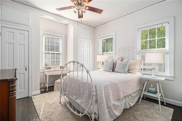 bedroom featuring multiple windows, ceiling fan, baseboards, and wood finished floors