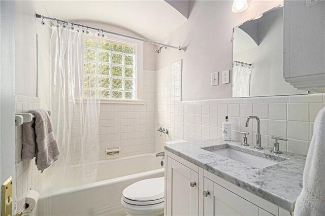 full bathroom featuring shower / tub combo with curtain, vanity, toilet, and tile walls