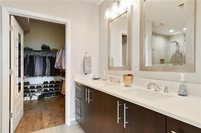 1080 Peachtree St NE Unit 1402, Atlanta, GA 30309 - bathroom with double vanity, tiled shower, a spacious closet, and wood finished floors