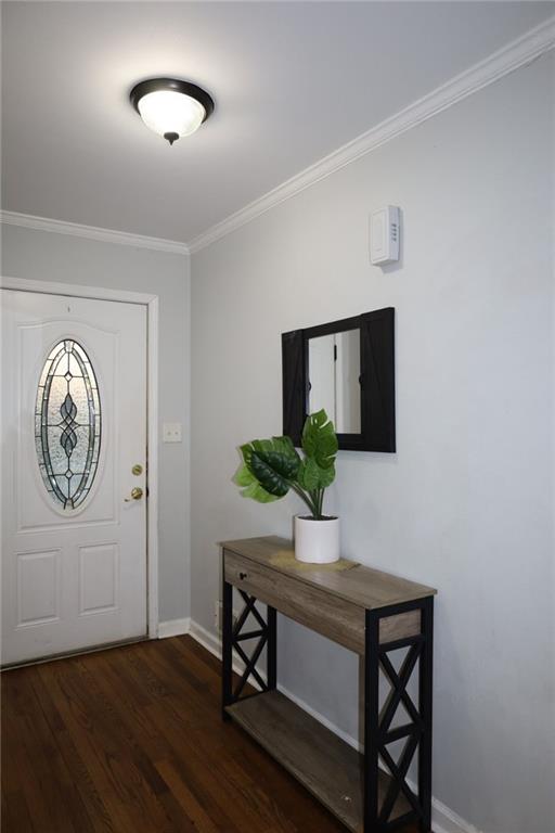 foyer with baseboards, wood finished floors, and ornamental molding