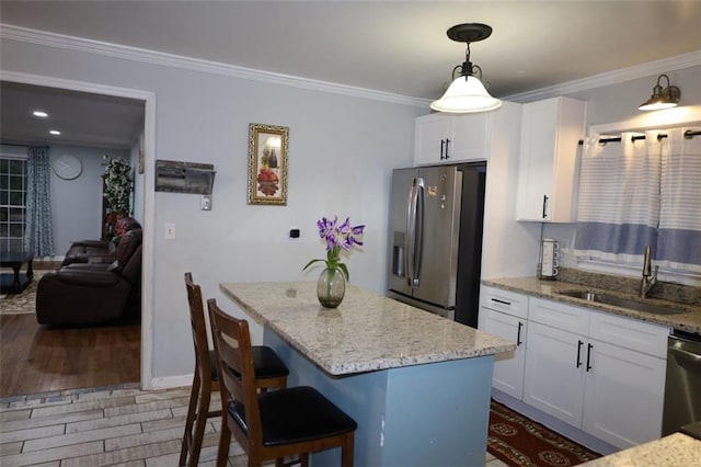 kitchen with a sink, ornamental molding, a kitchen island, and stainless steel appliances