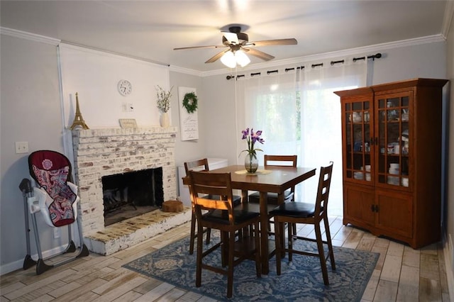 dining space with light wood-type flooring, a ceiling fan, ornamental molding, and a fireplace