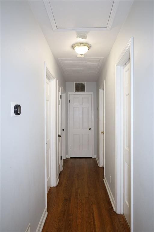 corridor featuring visible vents, attic access, dark wood-type flooring, and baseboards