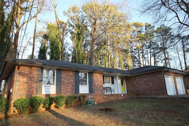 single story home featuring a front lawn, an attached garage, and brick siding