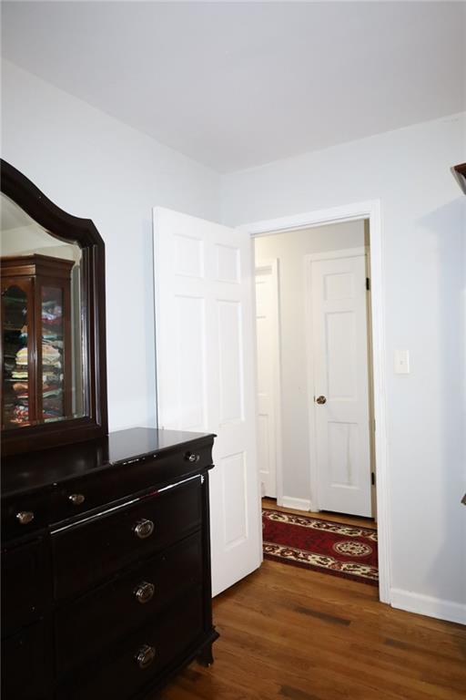 corridor with dark wood-type flooring and baseboards