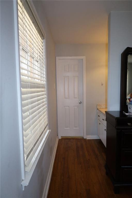 hallway featuring dark wood finished floors and baseboards