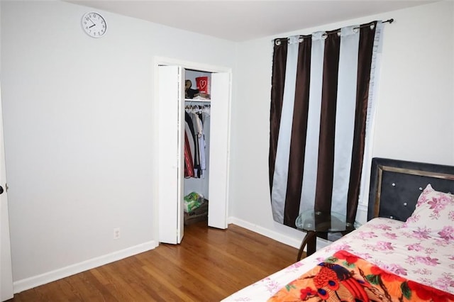 bedroom with a closet, baseboards, and wood finished floors